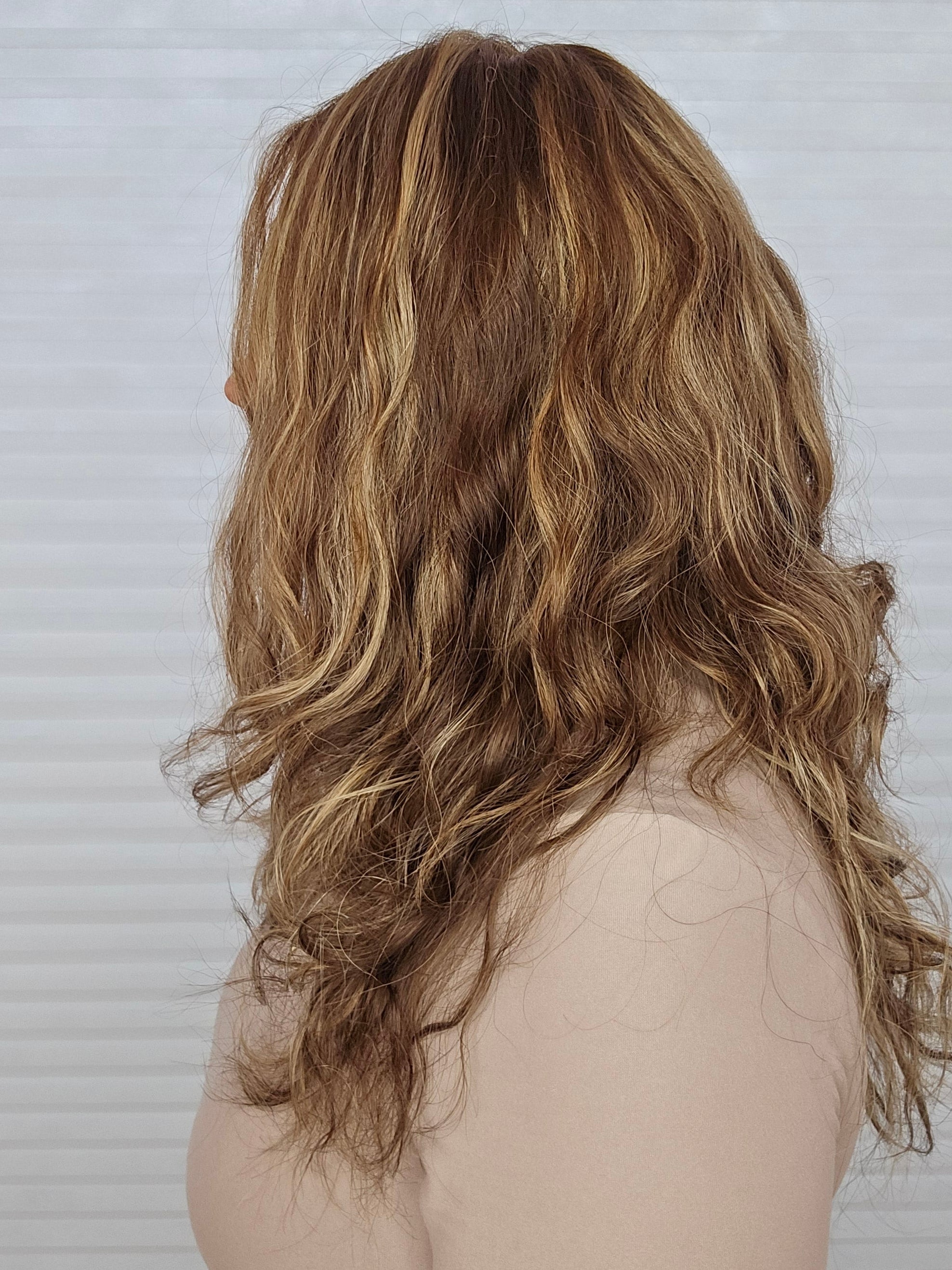 Woman with long, wavy hair wearing a 16-24 inch Bespoke wig from PUSH Hair in color Belle, side profile