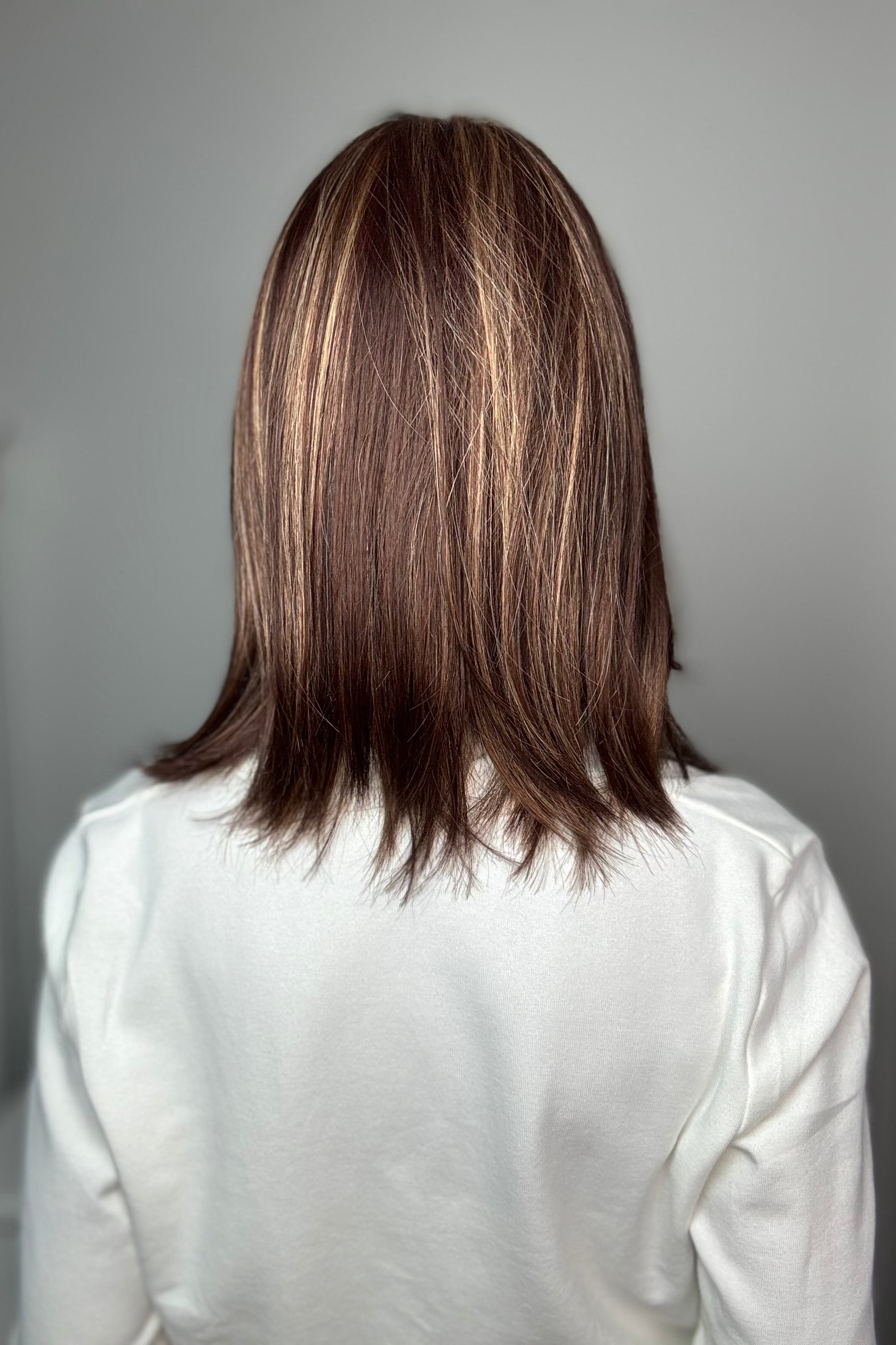 Woman with shoulder-length brown wig with bangs (Tatum by Amore in Auburn Sugar) back