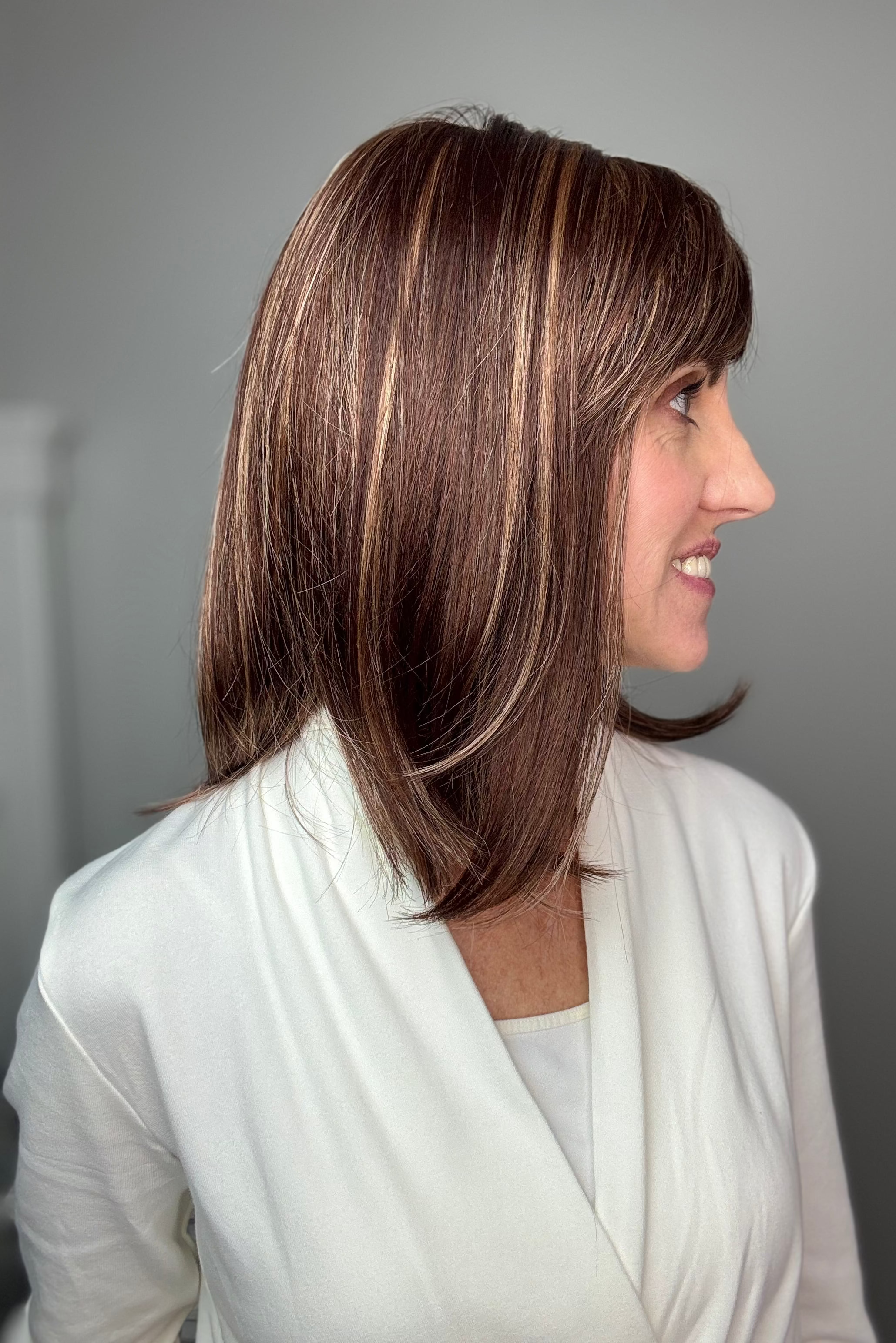 Woman with shoulder-length brown wig with bangs (Tatum by Amore in Auburn Sugar) side