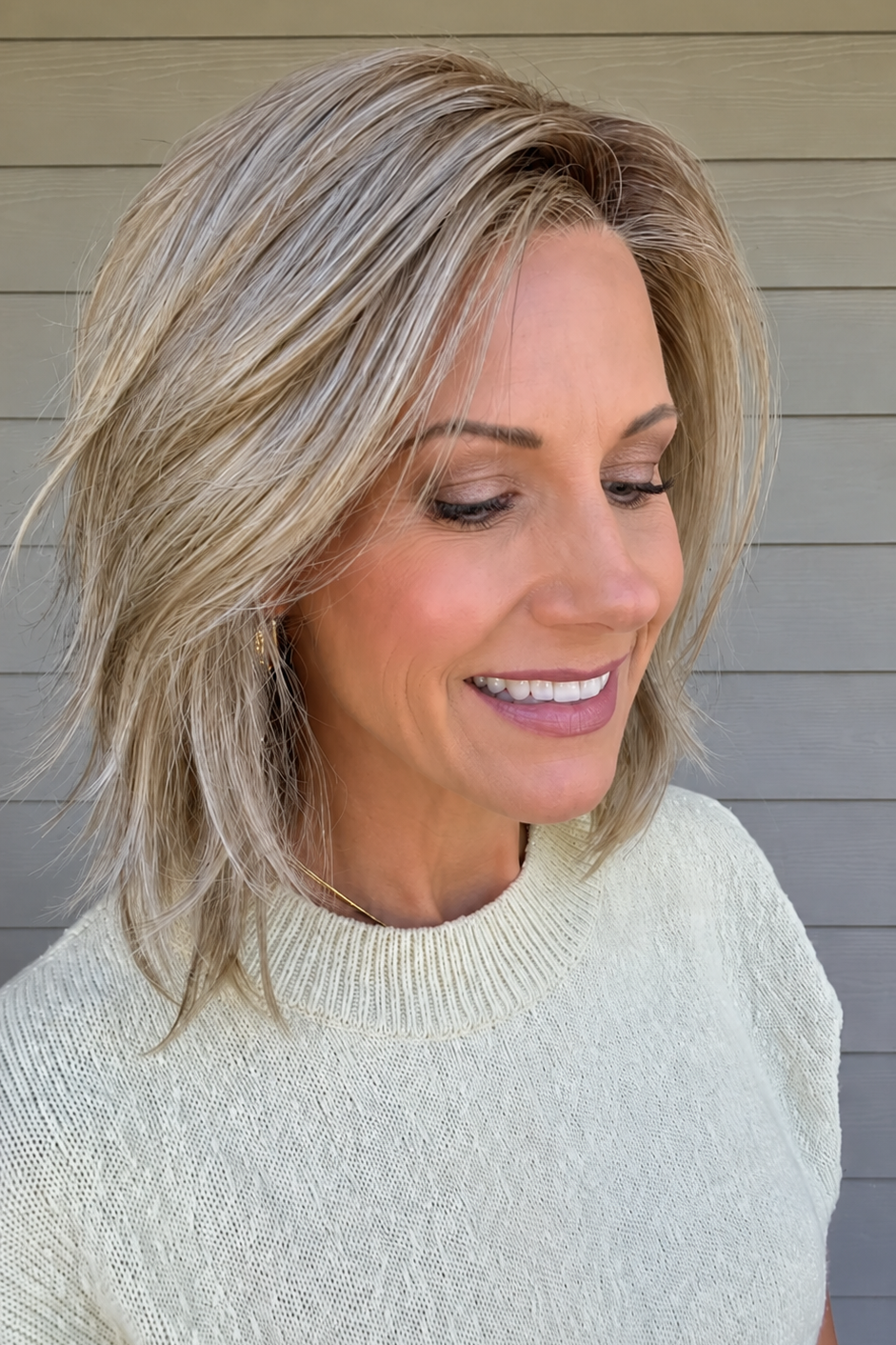 Woman with short blonde wavy wig (Rebecca by Belle Tress in color Sparkling Champagne)