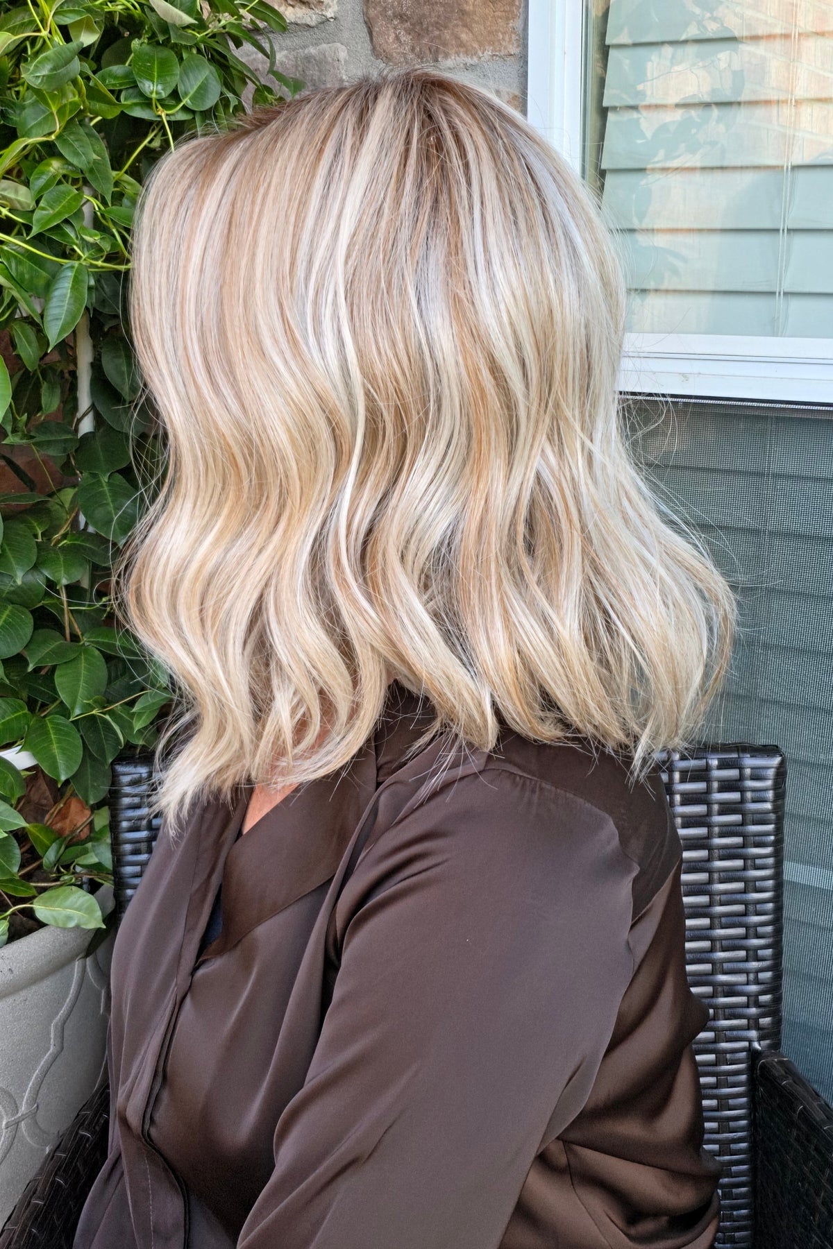 A woman with shoulder-length blonde wavy wig (Karlie by Belle Tress in Butterbeer Blonde R).