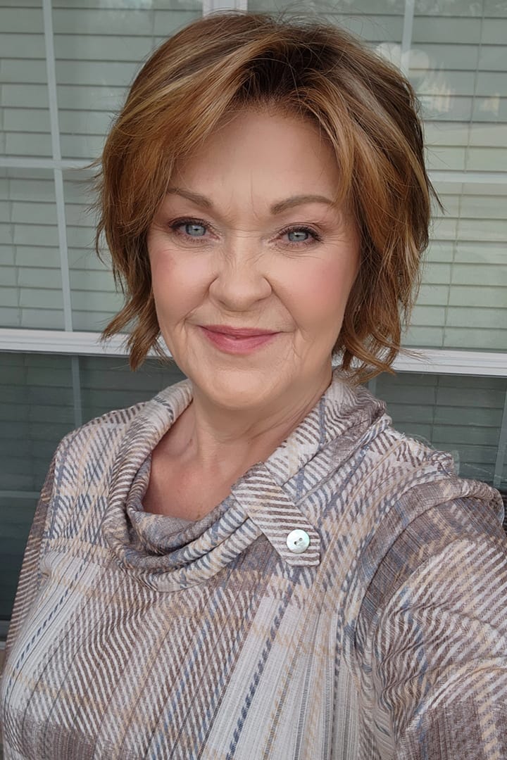 Woman with reddish-brown chin-length bob wig (Marni by Belle Tress in Butter Pecan)