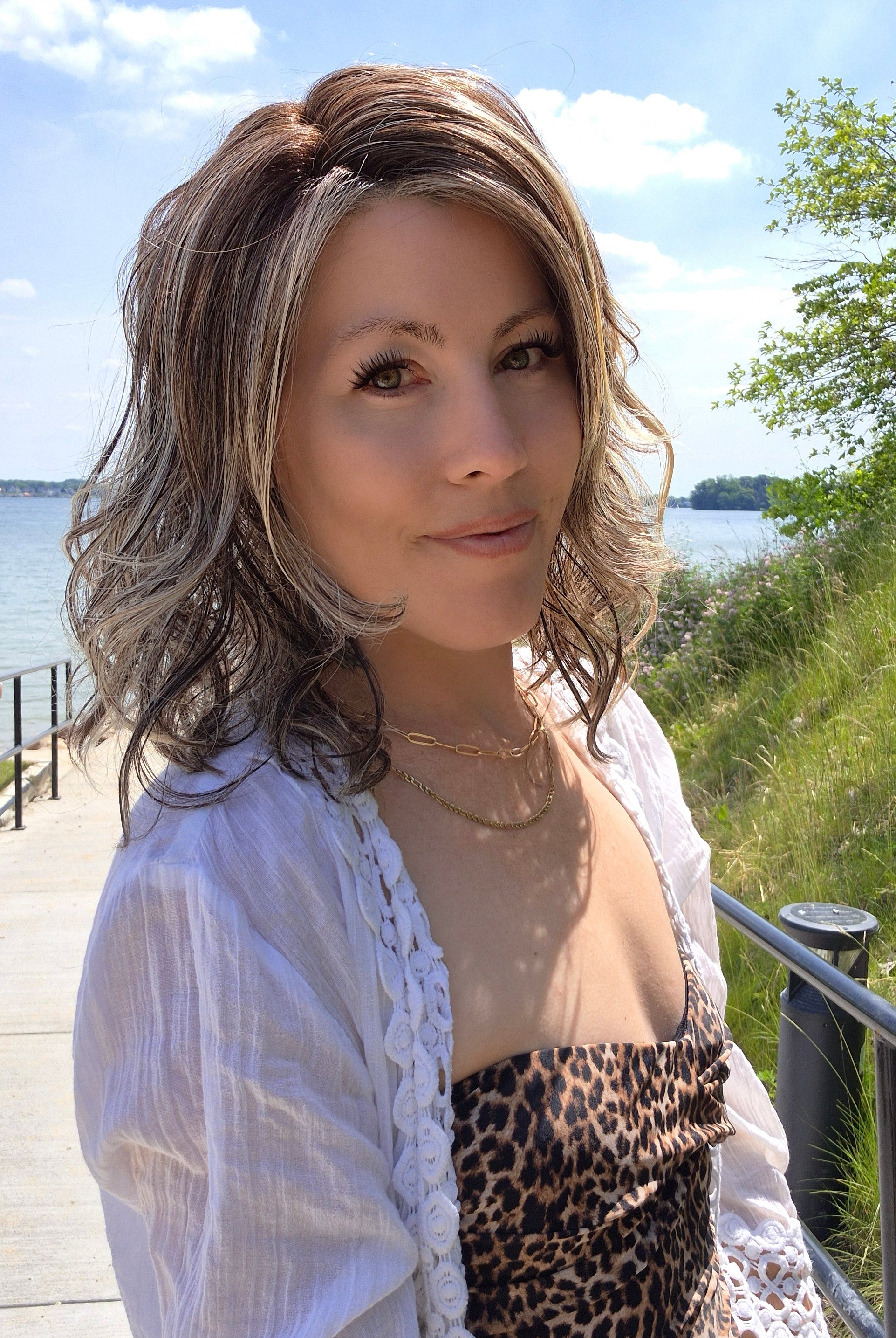 Woman wearing shoulder-length curly wig (Morgan by Belle Tress in color Buttered Toast).