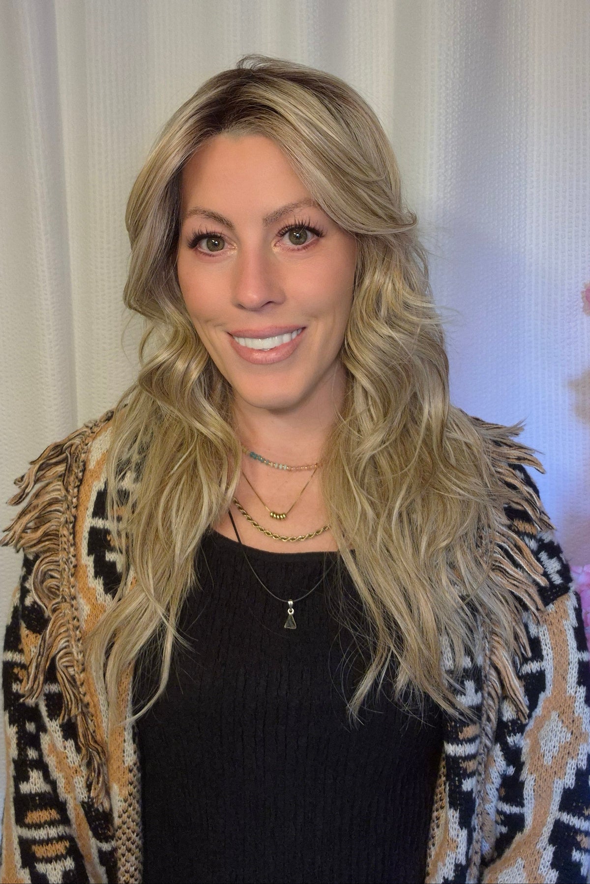 A woman with long blonde wavy wig withh bangs (Muse by Belle Tress in color Butterbeer R).