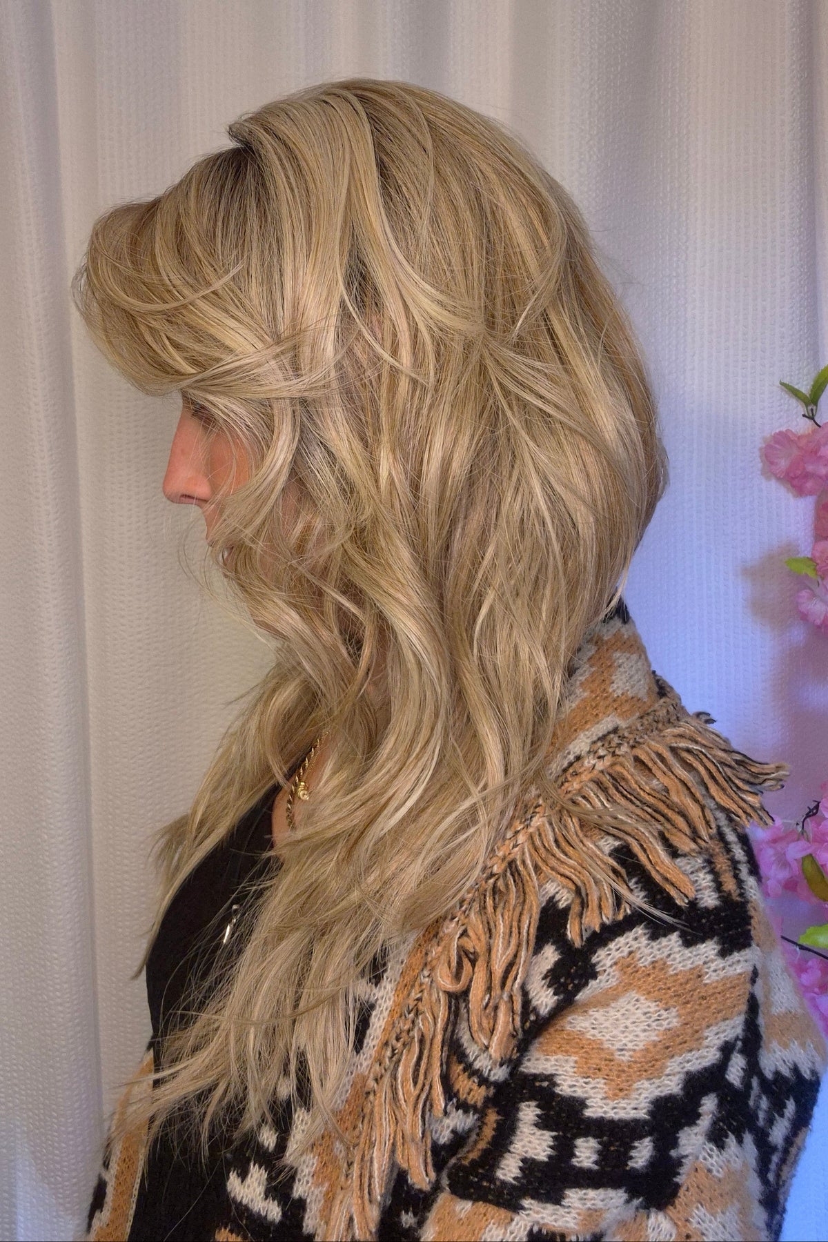 A woman with long blonde wavy wig withh bangs (Muse by Belle Tress in color Butterbeer R).