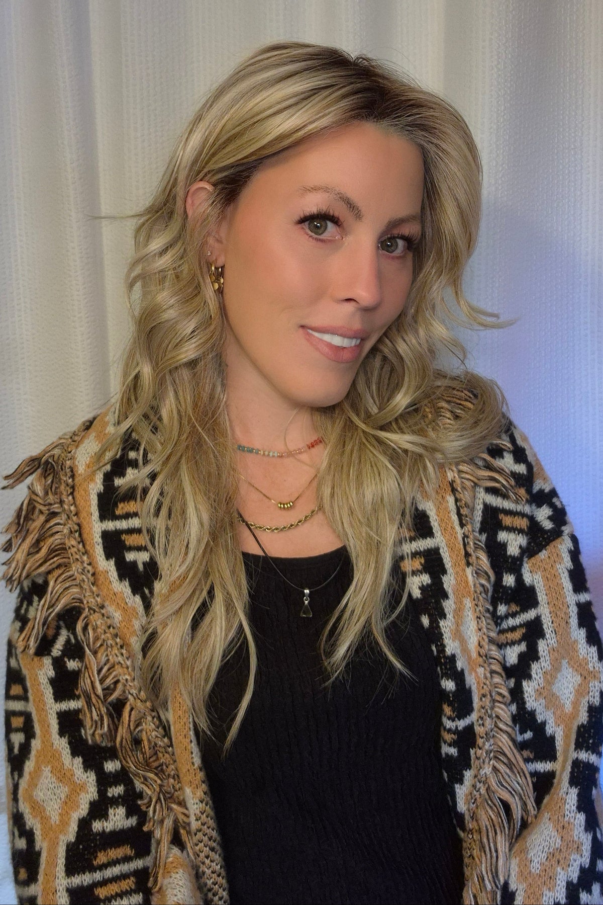 A woman with long blonde wavy wig withh bangs (Muse by Belle Tress in color Butterbeer R).