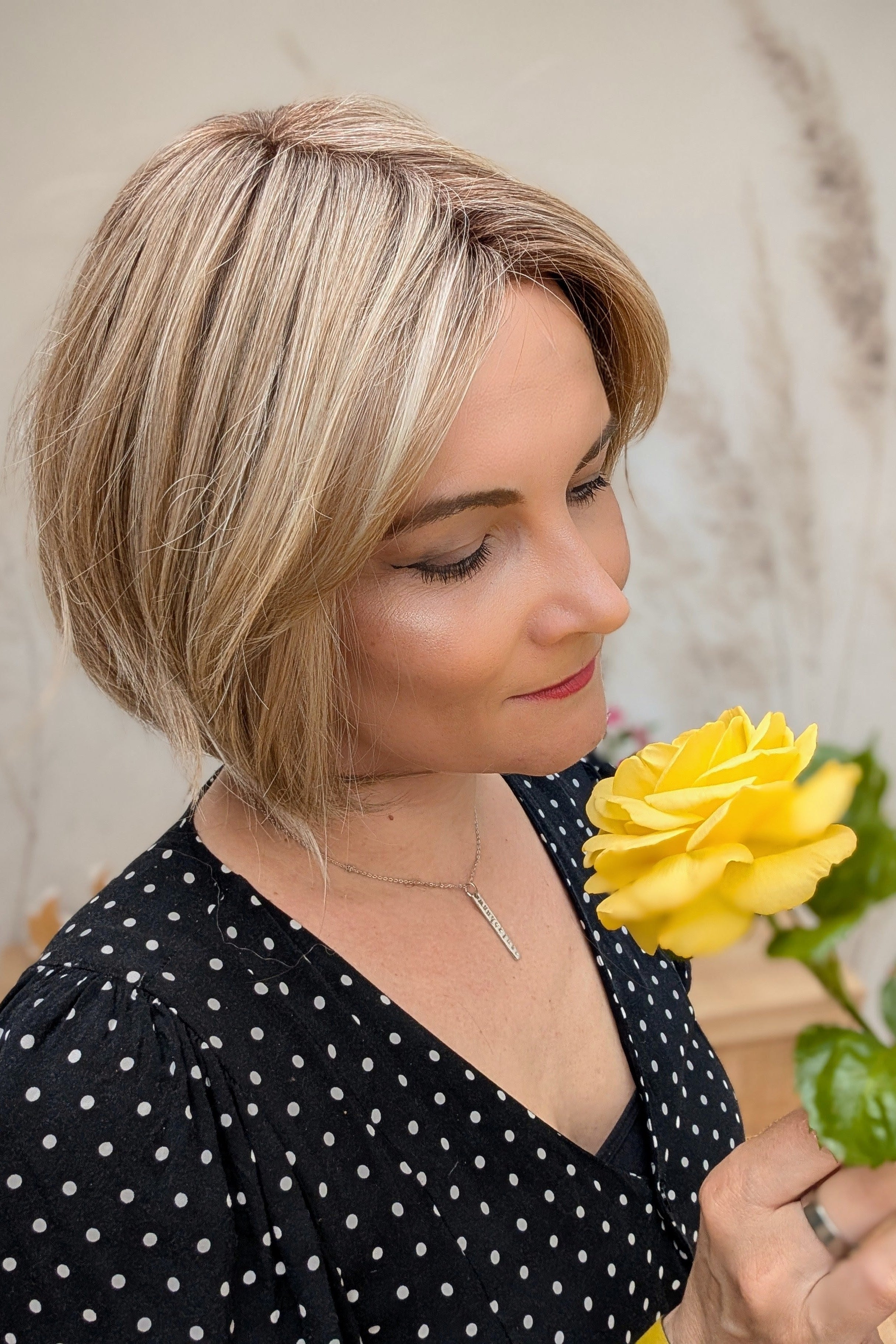 Woman wearing chin-length angled blonde bob wig (Clover by Estetica in RH18/88 RT8)