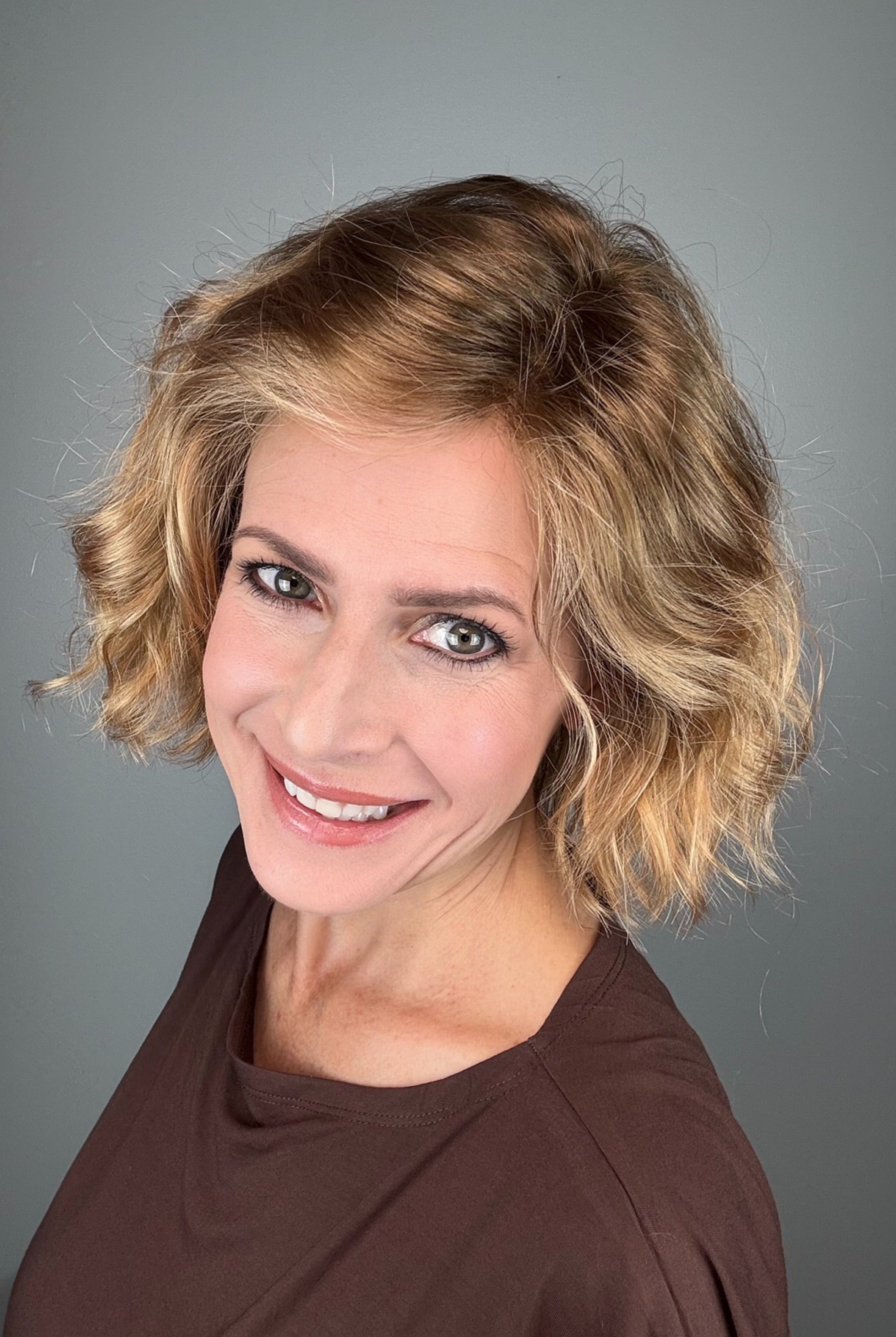 Woman wearing chin-length wavy rooted blonde bob wig (Dance by Ellen Wille in Toffee Blonde Tipped).