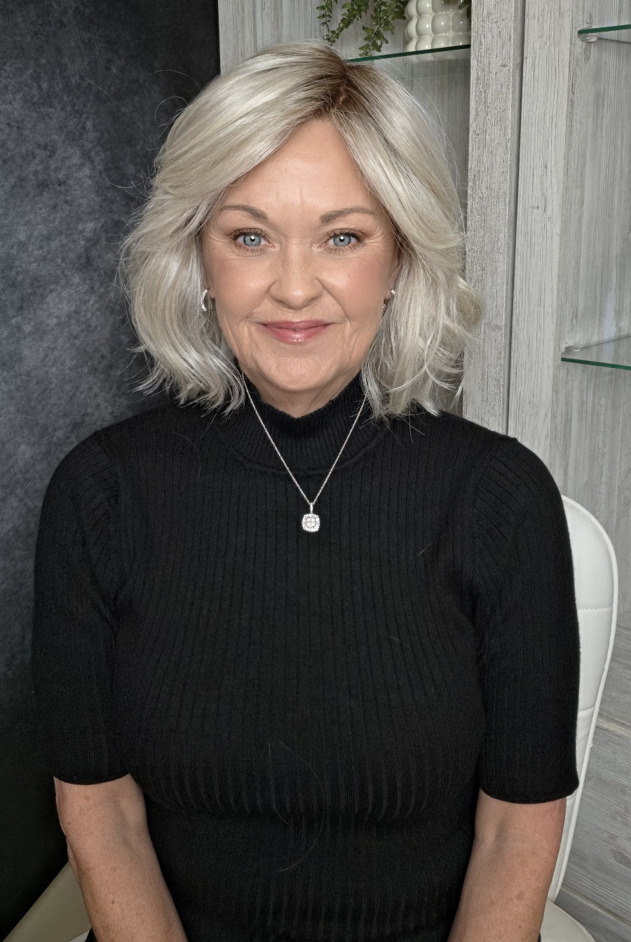 A woman with shoulder-length platinum blonde wig (Elle Mono by Ellen Wille in Silver Blonde R).