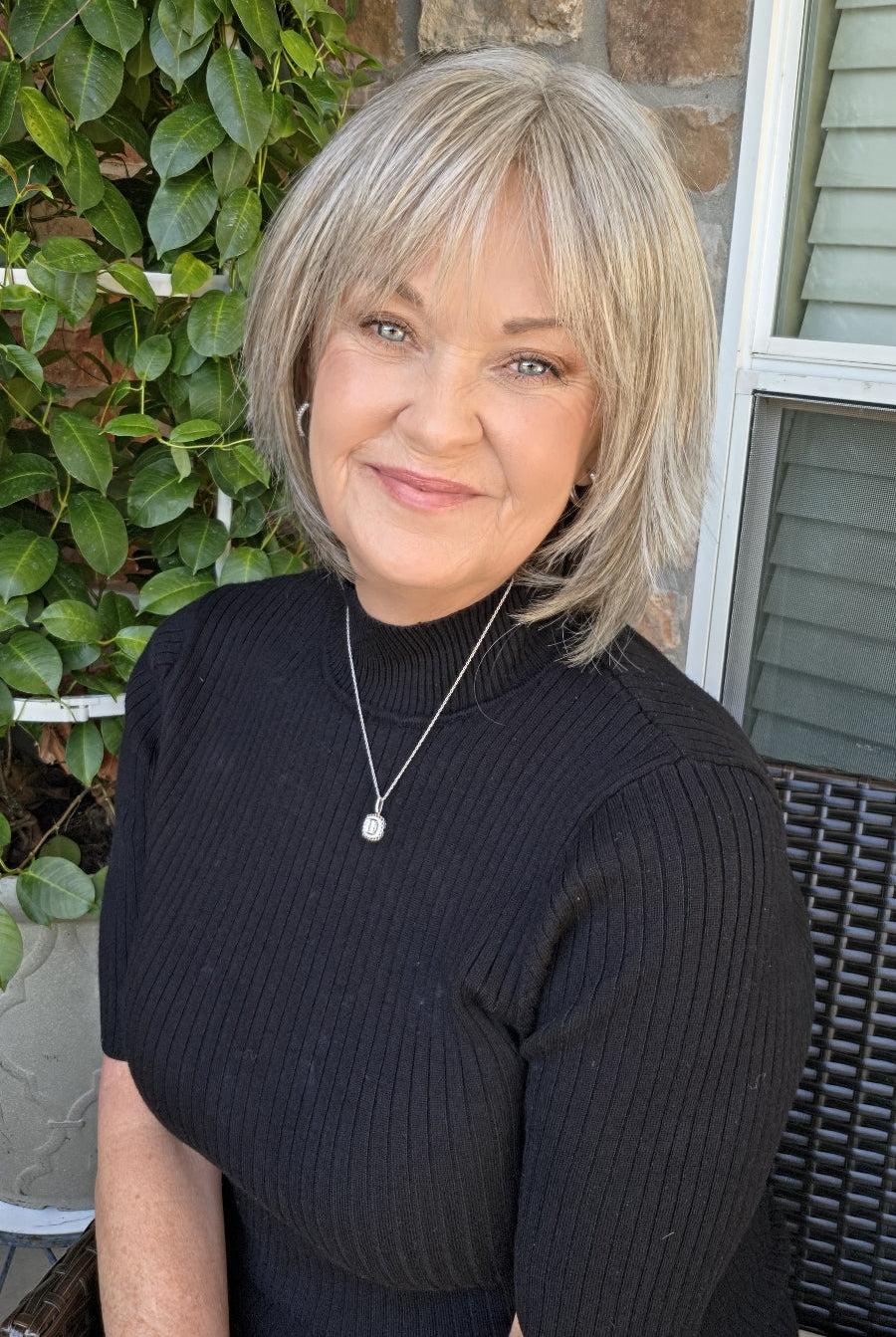A woman with short grey wig (Tess Mono by Ellen Wille in color Stone Gray Mix).