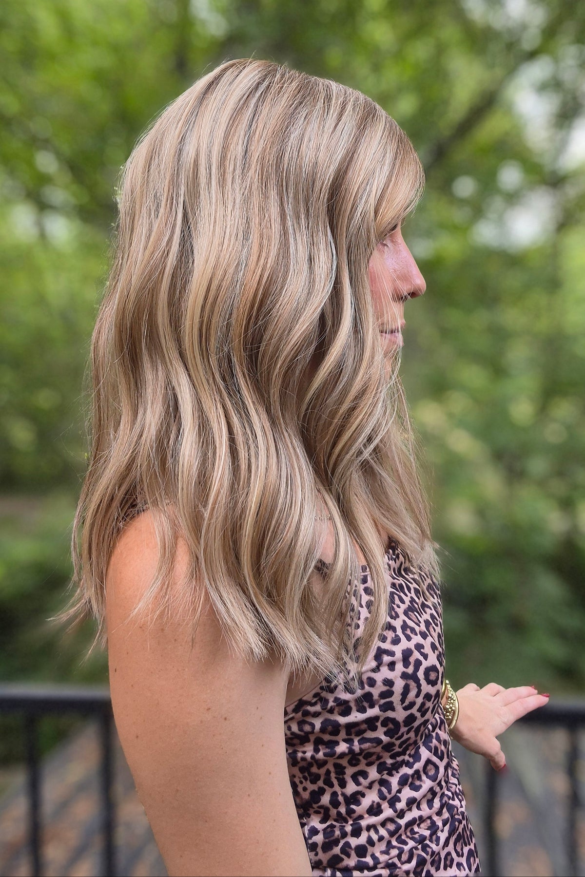 A woman with blonde wavy hair wearing a leopard print dress (Morgan by Jon Renau in Malibu Blonde)