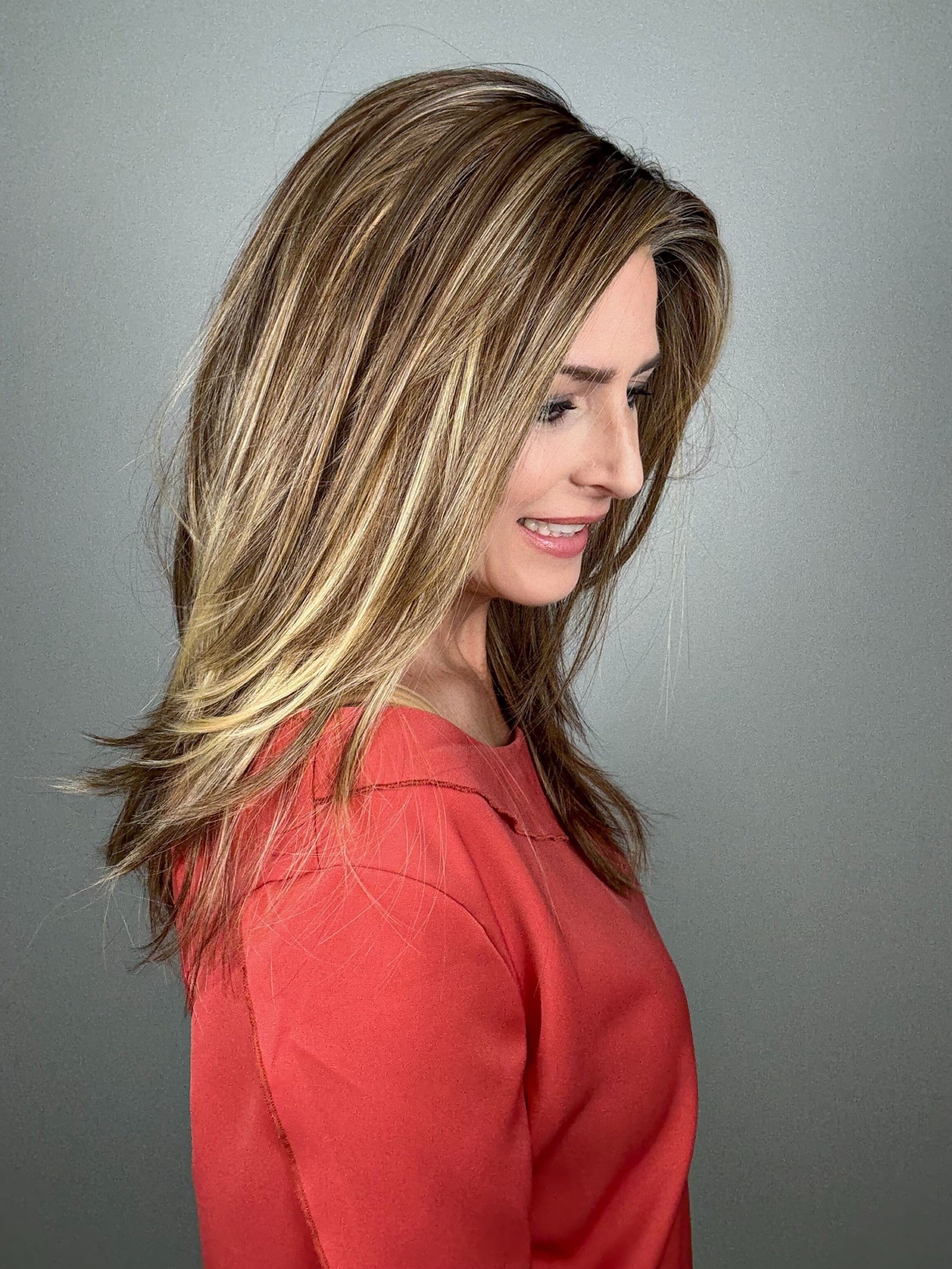 Woman wearing long layered wig (Mirror Moment by Gabor in Honey Pecan) side