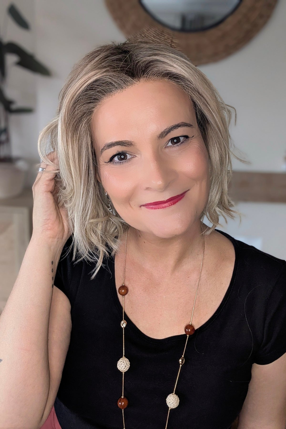 A woman with short blonde wavy bob wig (Naples by Belle Tress in color Crushed Almond Blonde R).