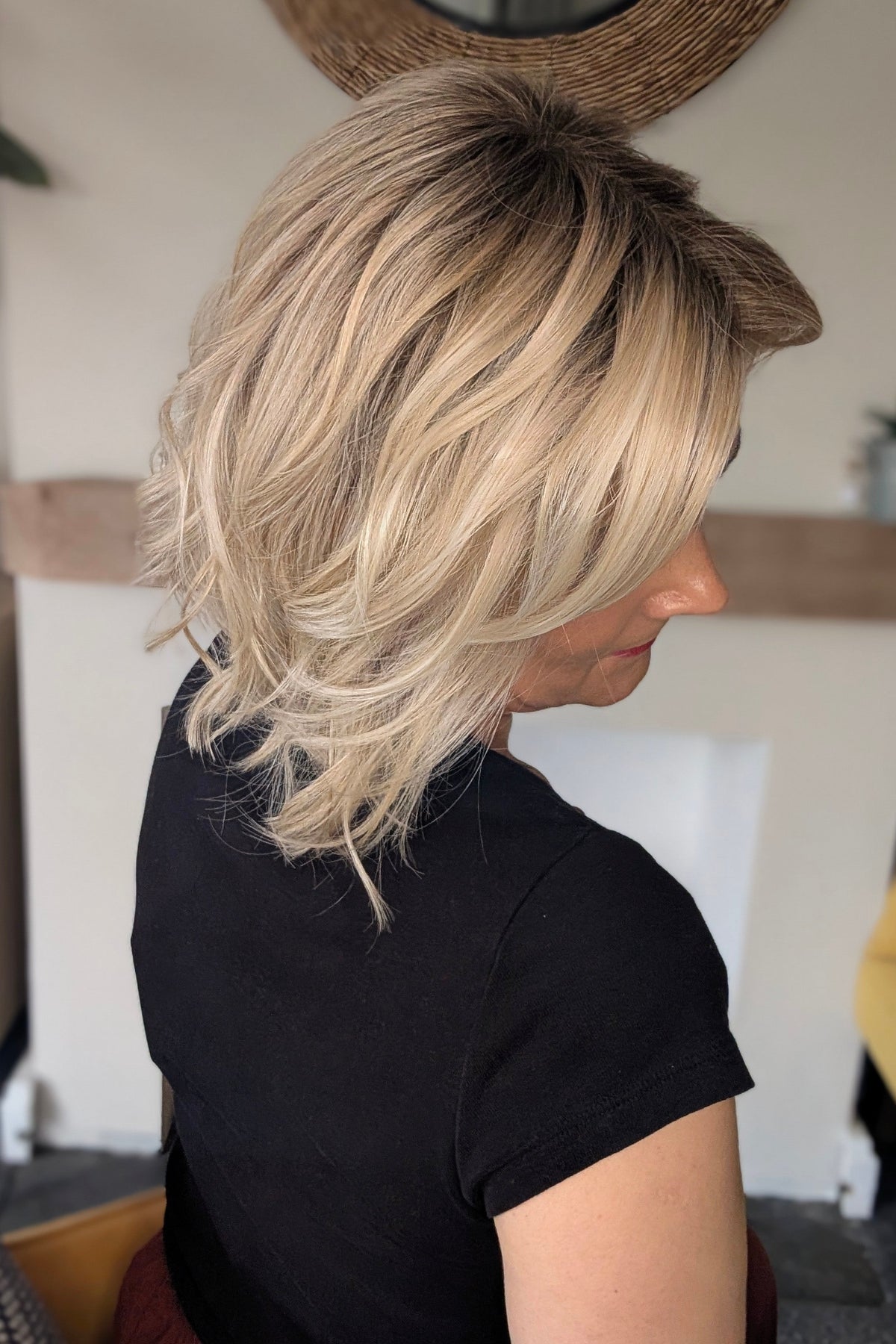 A woman with short blonde wavy bob wig (Naples by Belle Tress in color Crushed Almond Blonde R).