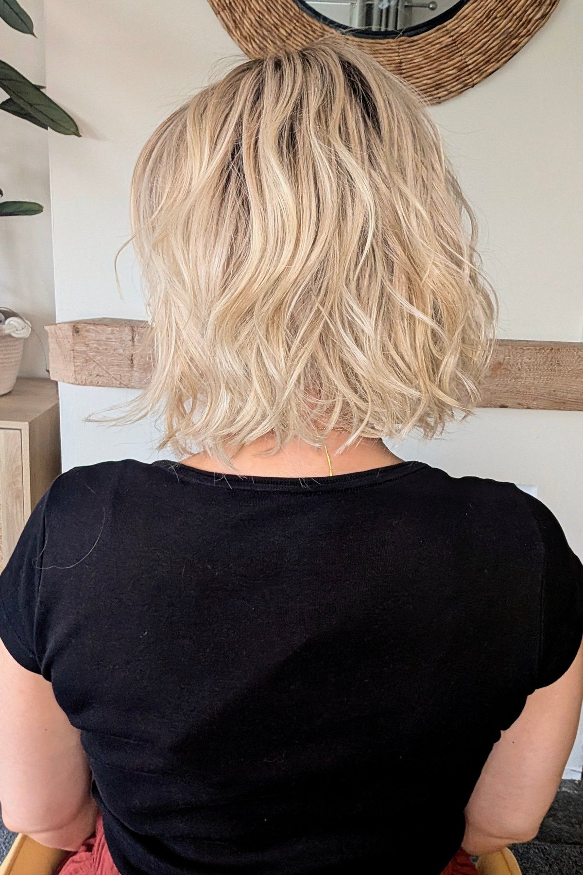 A woman with short blonde wavy bob wig (Naples by Belle Tress in color Crushed Almond Blonde R).