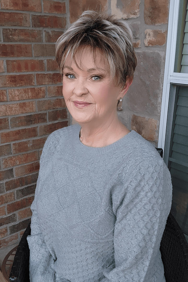 Woman wearing short rooted gray pixie wig (Noriko's Rin in color Snowy Umber)