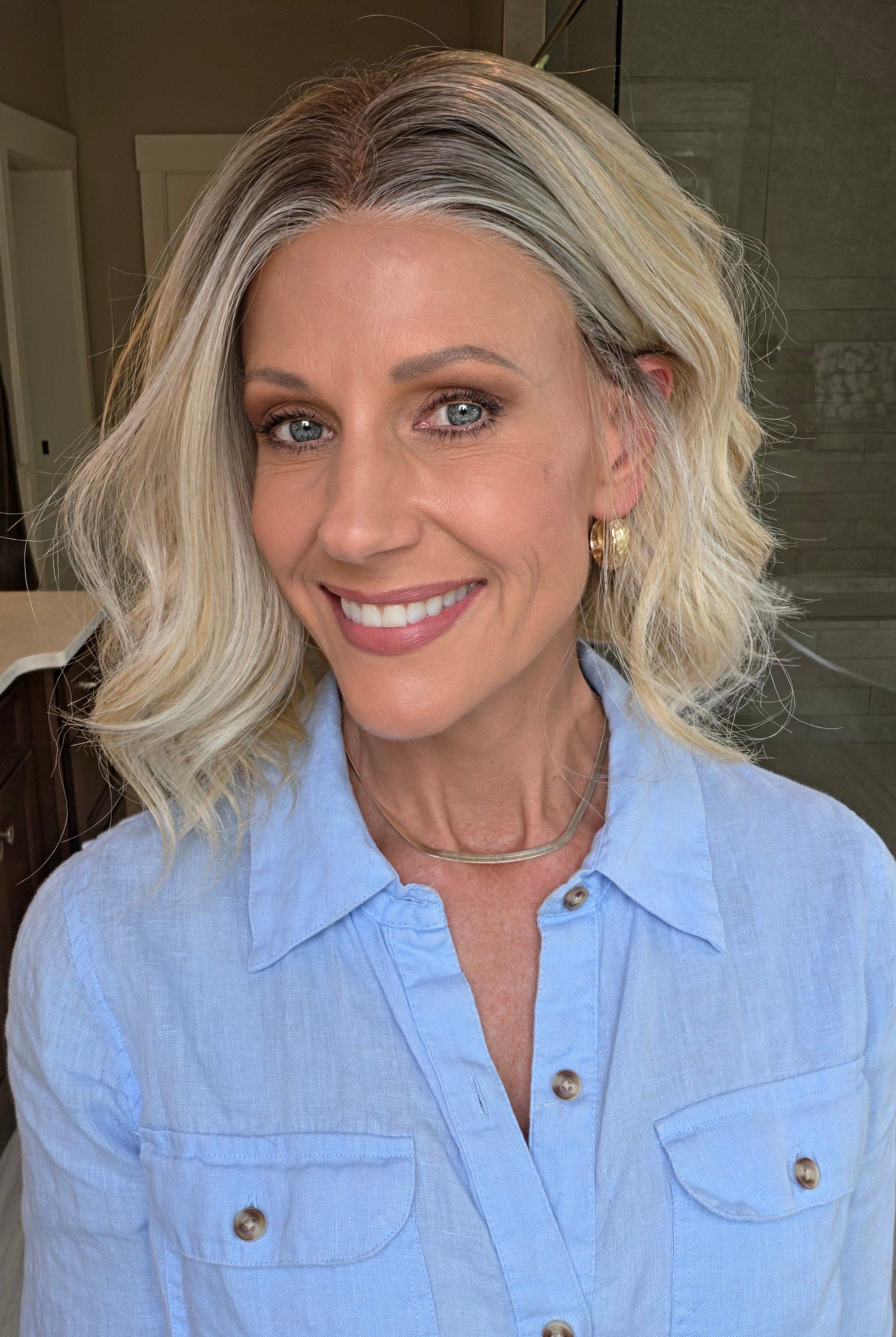 Woman wearing shoulder length curly blonde wig (Brielle by PUSH Hair in color Golden Champagne R)