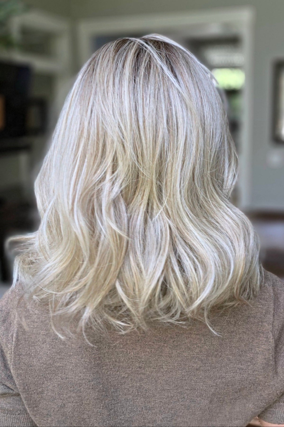 A smiling woman with shoulder-length wavy blonde wig (Keeley by PUSH Hair in color Champagne Blonde R).