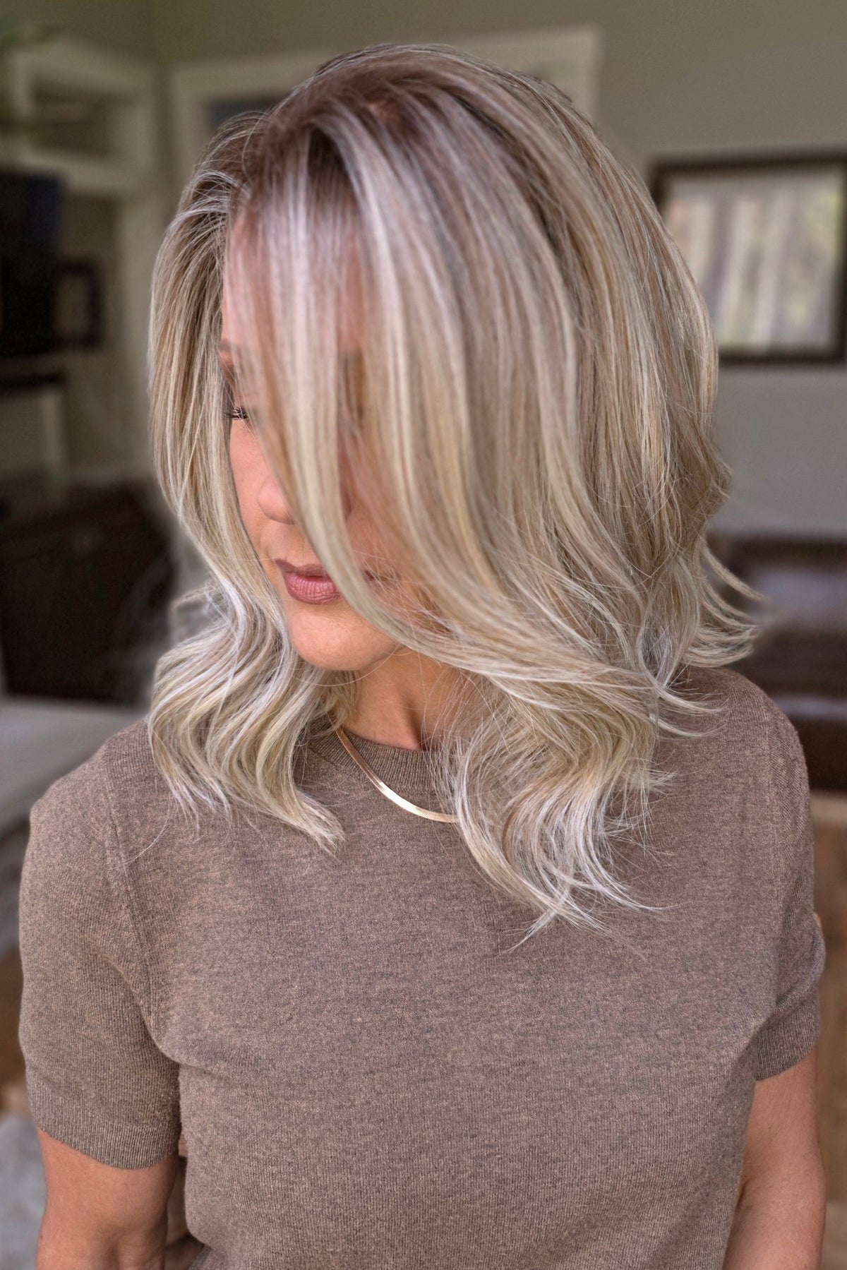 A smiling woman with shoulder-length wavy blonde wig (Keeley by PUSH Hair in color Champagne Blonde R).