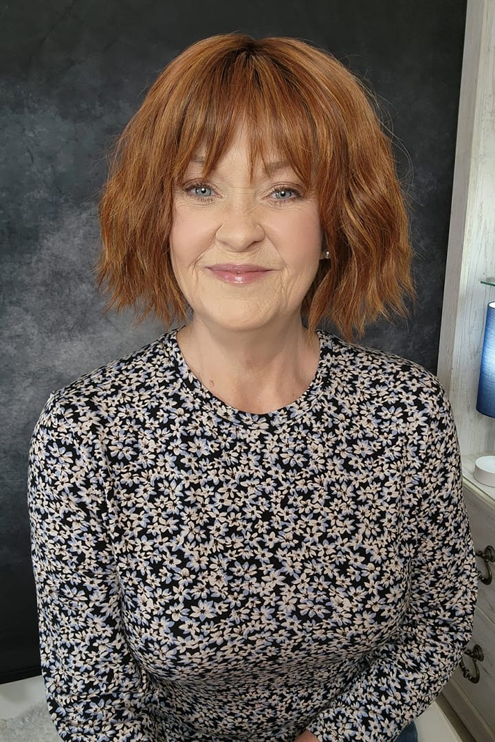 Woman wearing chin length bob with bangs (Rene of Paris' Rosanna in color Autumn Sunrise)