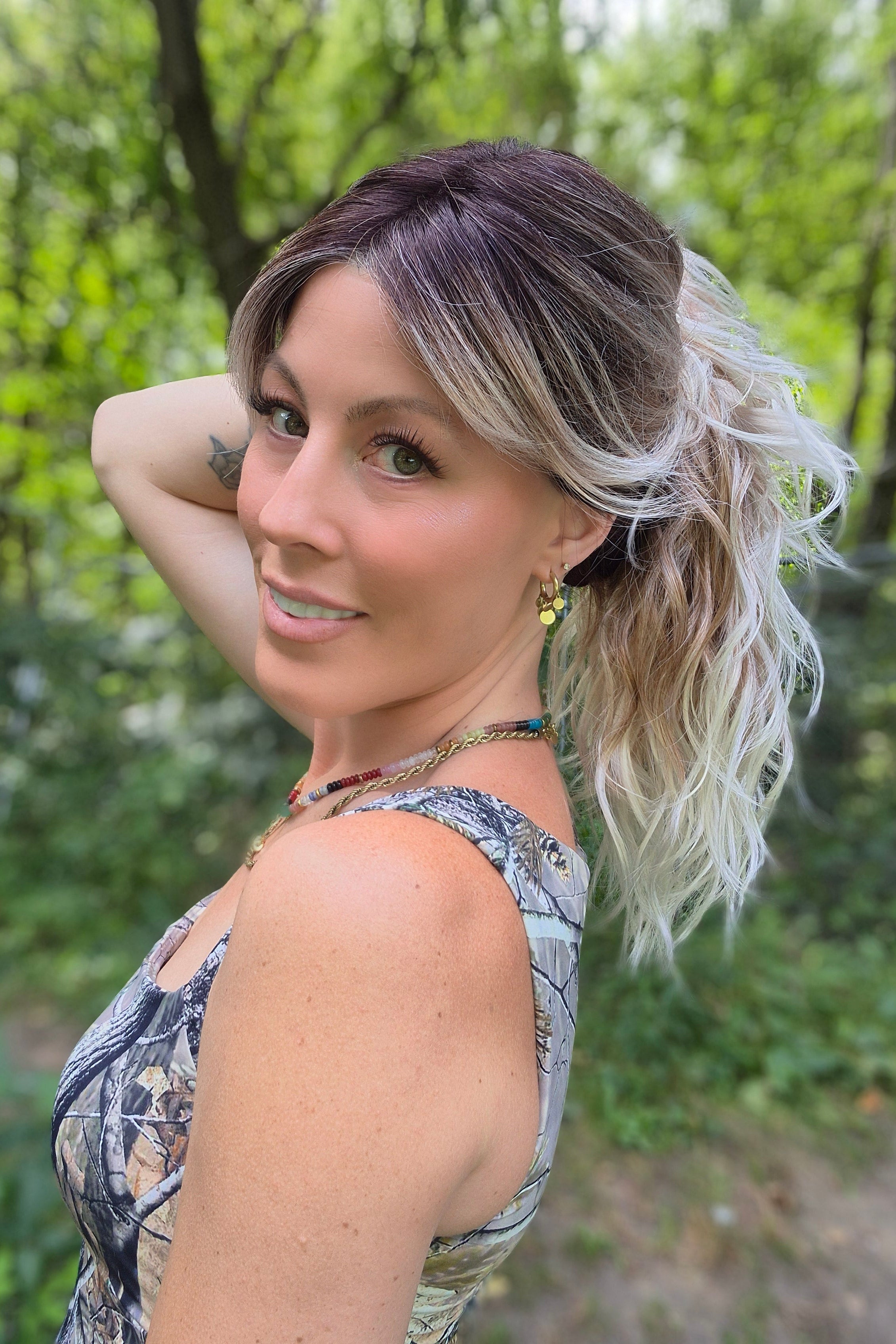 A woman with long blonde-highlighted hair wearing a camouflage-patterned tank top (Phillip by Rene of Paris in Melted Marshmallow R).