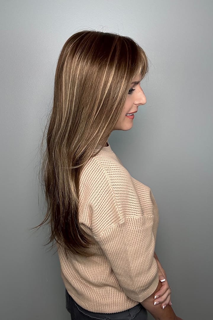 Woman wearing long brunette wig with bangs and highlights (Stevie by Amore in Honey Wheat) side