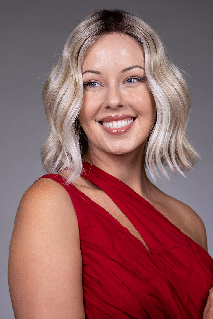 Tulip by Belle Tress chin-length bob wig with soft blonde waves, money piece highlights, and a wide center part.