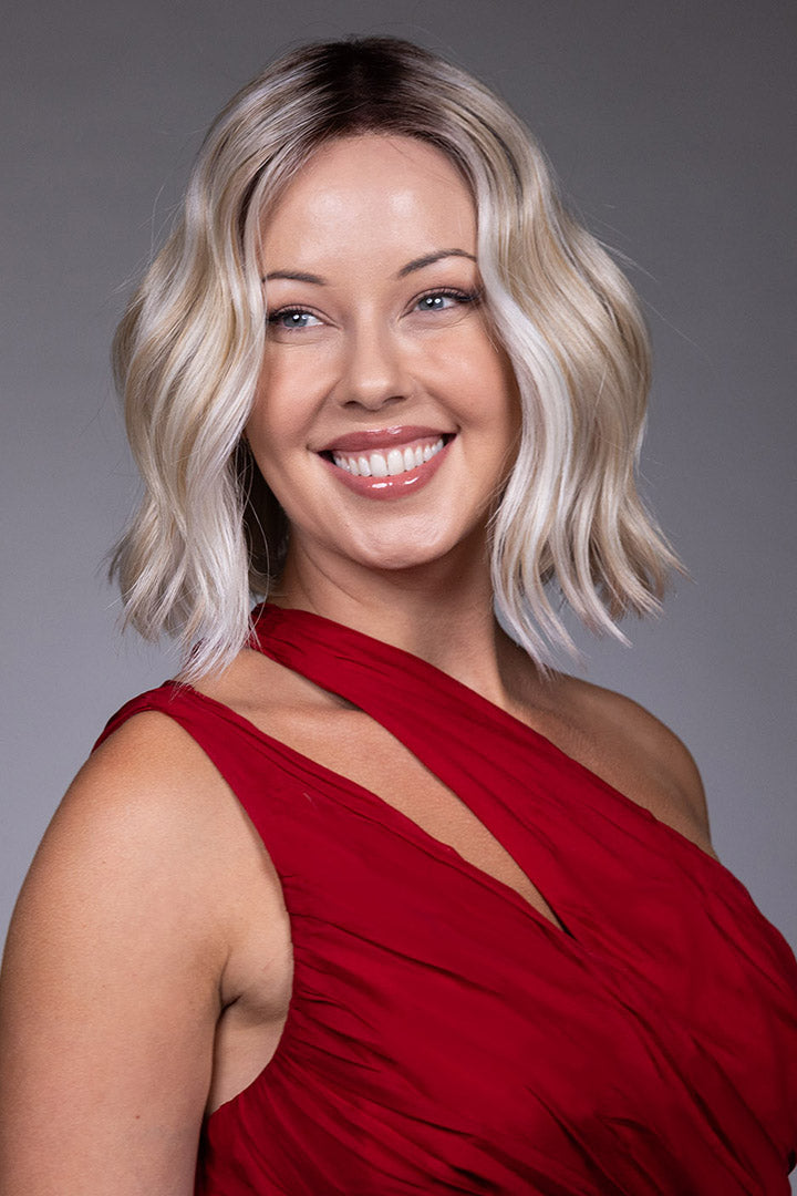 Tulip by Belle Tress chin-length blonde bob wig with soft beach waves, center part, and face-framing money piece highlights.