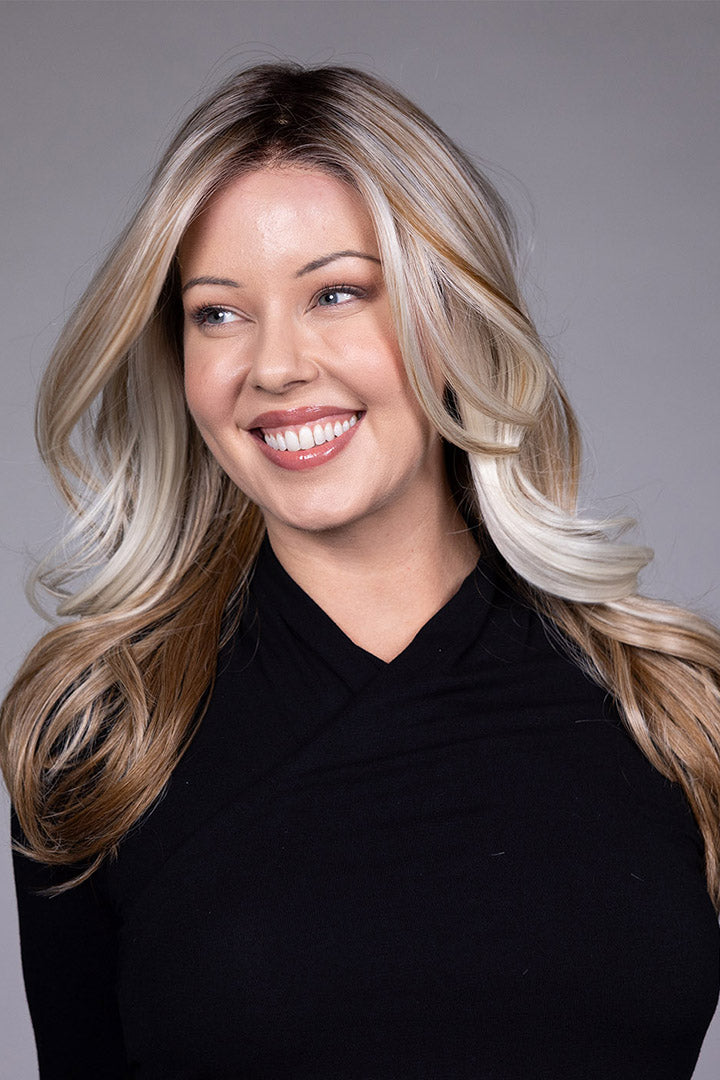 Wisteria by Belle Tress long wavy synthetic wig with blonde money piece highlights and a natural lace front.