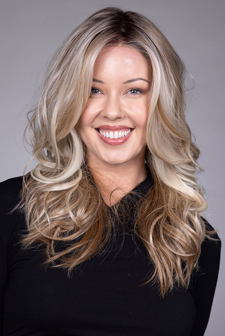 Wisteria by Belle Tress long wavy synthetic wig with face-framing blonde money piece highlights and a lace front.