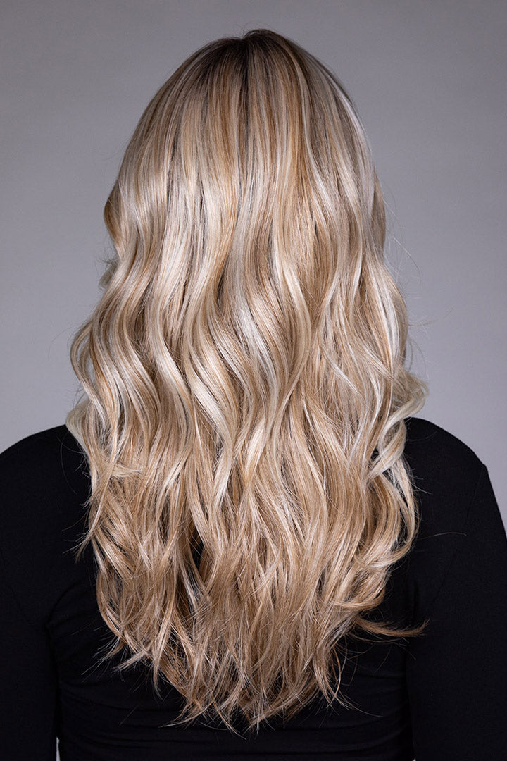 Back view of Wisteria by Belle Tress, a long synthetic wig with flowing blonde waves and soft, feathered layers.