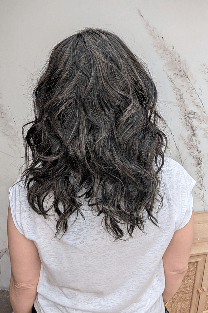 Woman wearing curly shouldar length (Belle Tress' Westwood in Coolest Dark Brown R) back
