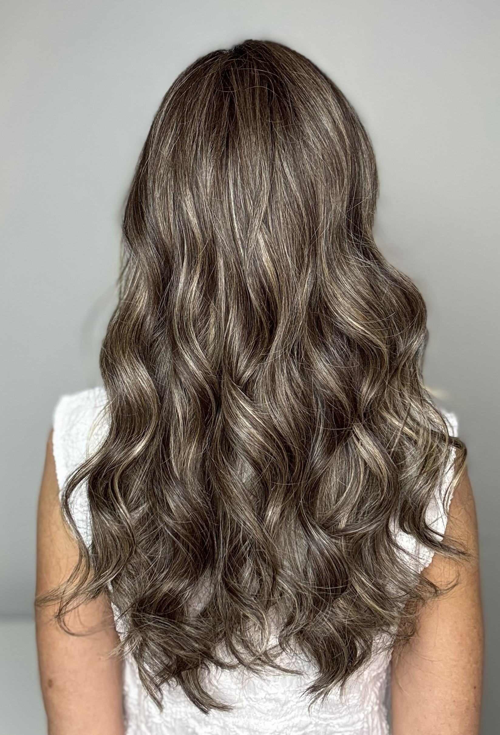 Woman with long, wavy brunette wig with highlights (Witherspoon by Belle Tress in Truffle Cream R)