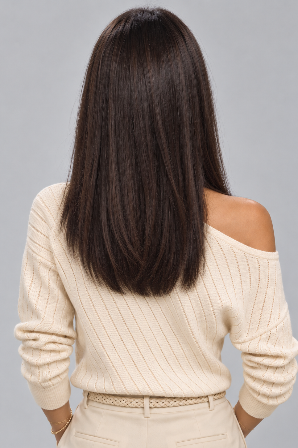 Woman wearing Gisele human hair wig by PUSH in color Noir and a cream off the shoulder knit top against a light grey background - front view.