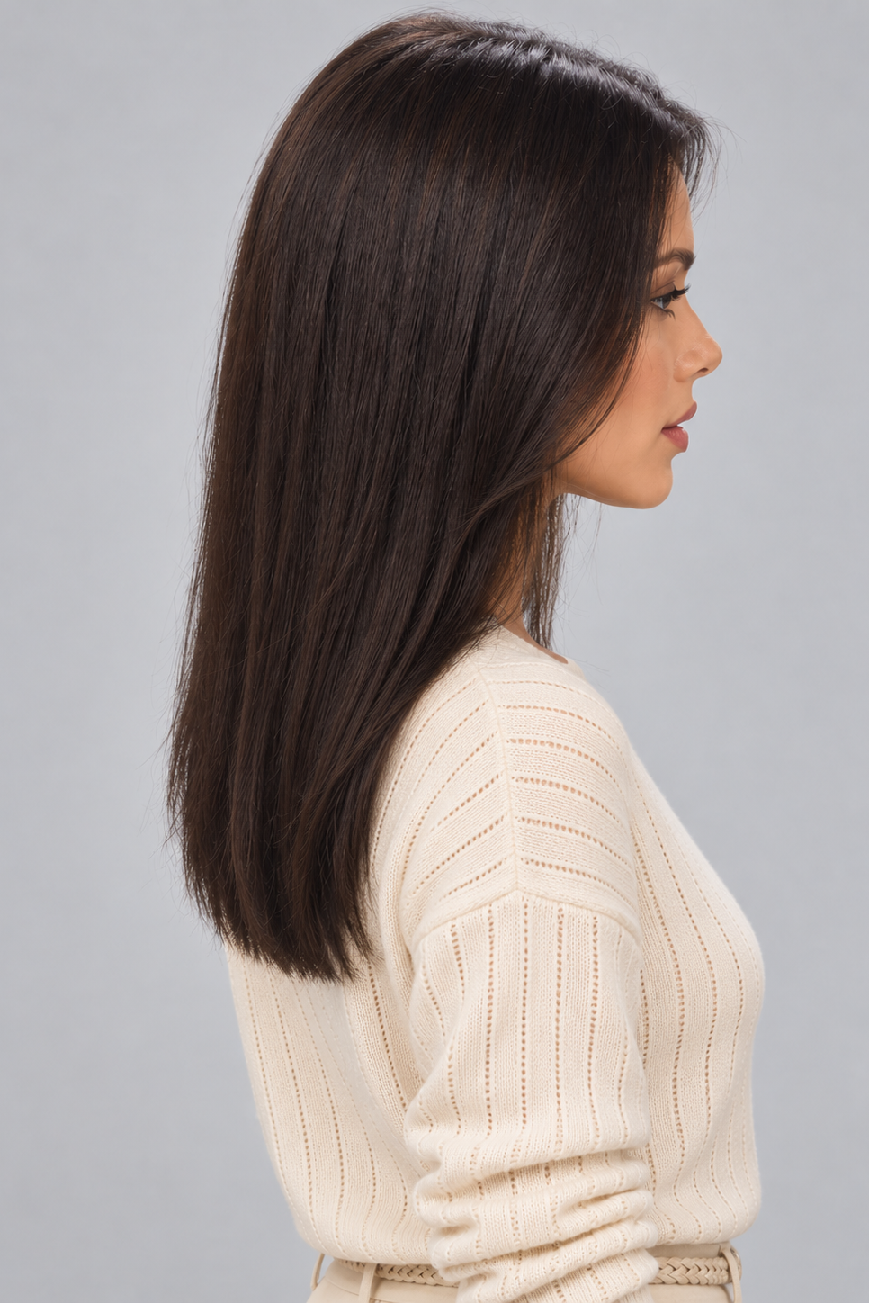 Woman wearing Gisele human hair wig by PUSH in color Noir and a cream off the shoulder knit top against a light grey background - right side view.