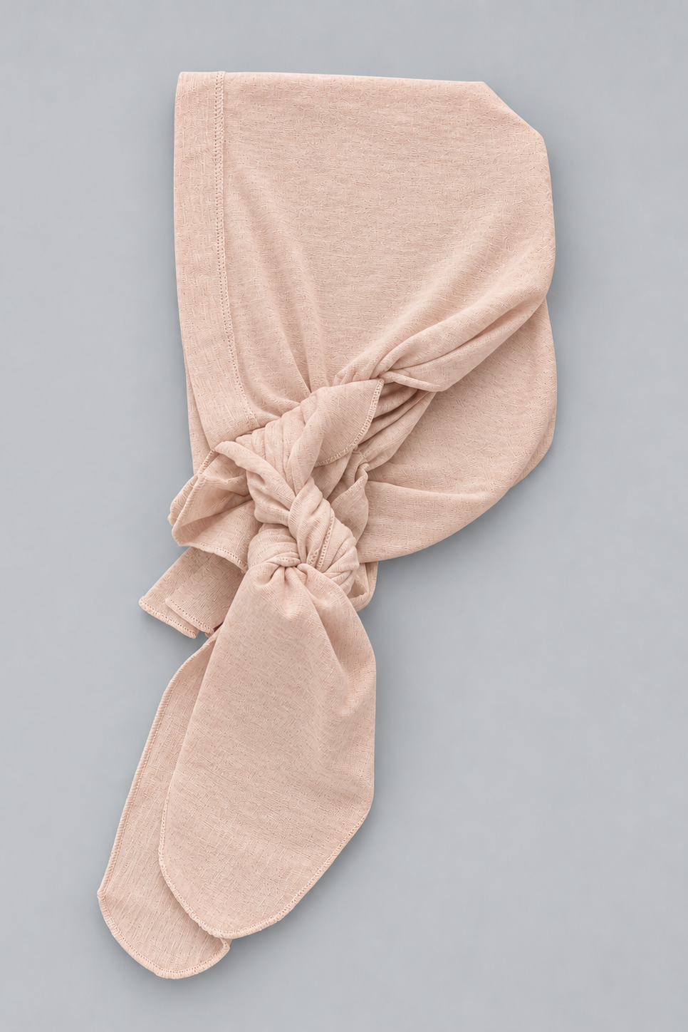 A soft amber melange bamboo head covering or turban-style cap laying flat against a plain light gray studio background.