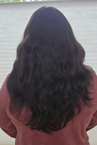 Woman with long, dark hair wearing a red top against a white background
