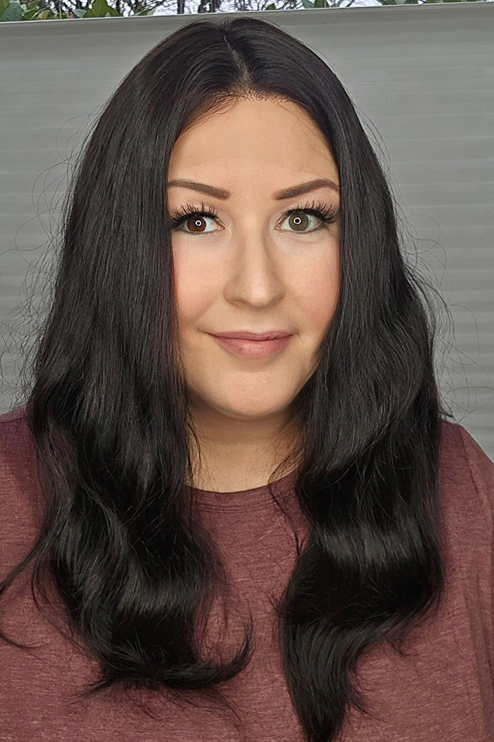 Woman with long black hair wearing a maroon top against a neutral background