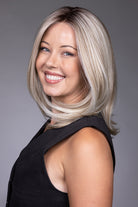 Adriana by Belle Tress layered blonde bob wig with lace front and monofilament top on a smiling model.