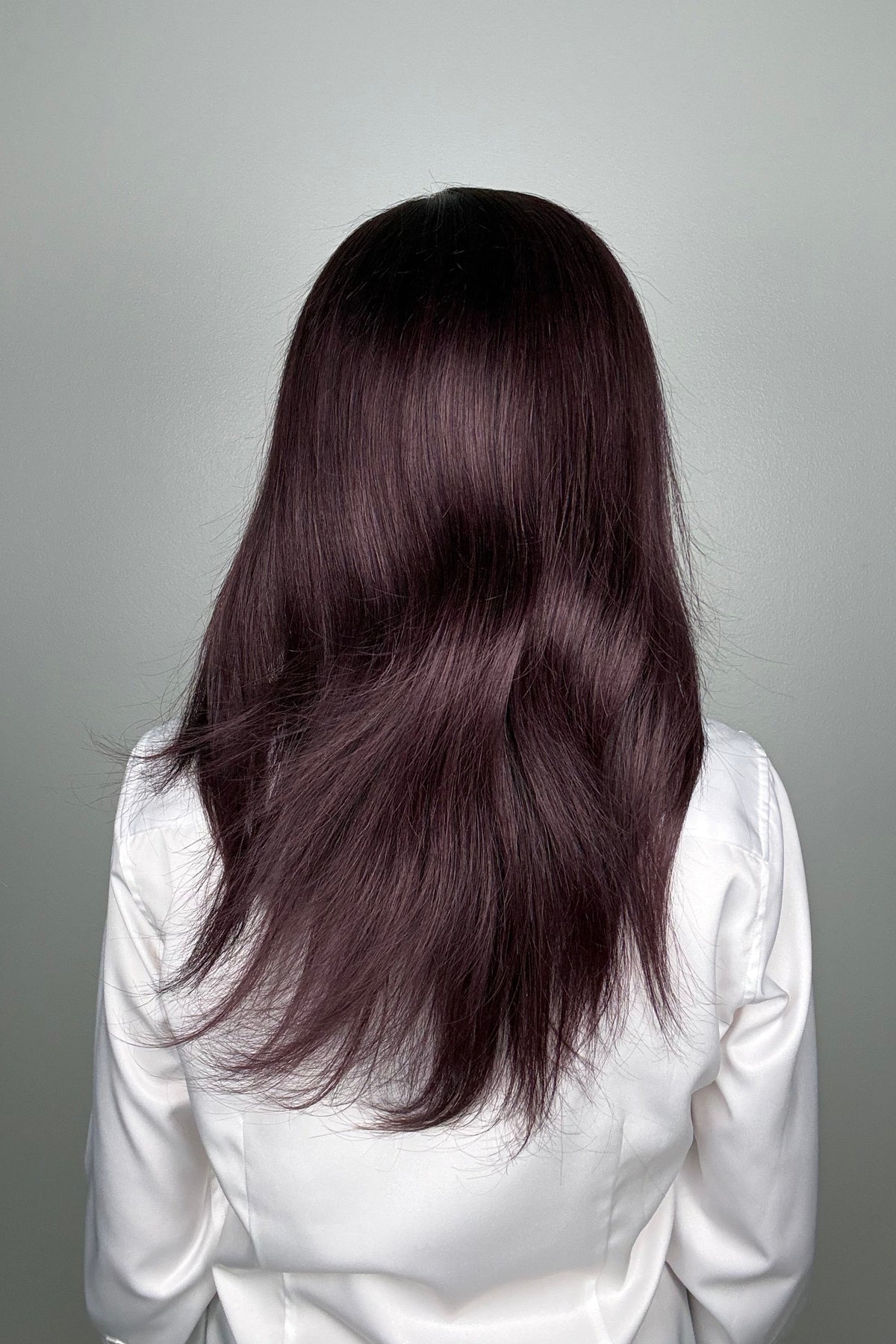 A woman with long, dark purple hair wearing a white button-down shirt (Adeline by PUSH Hair in color Belle Violette).