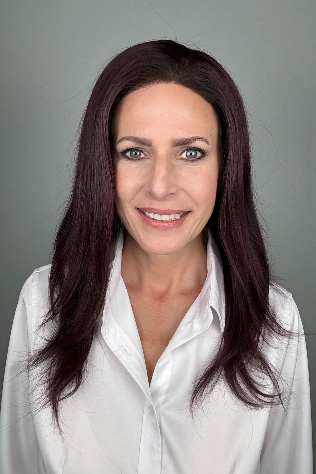A woman with long, dark purple hair wearing a white button-down shirt (Adeline by PUSH Hair in color Belle Violette).