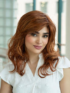Woman wearing Alana synthetic wig by Envy in color Lighter Red wearing a white blouse in an indoor setting. Front view.