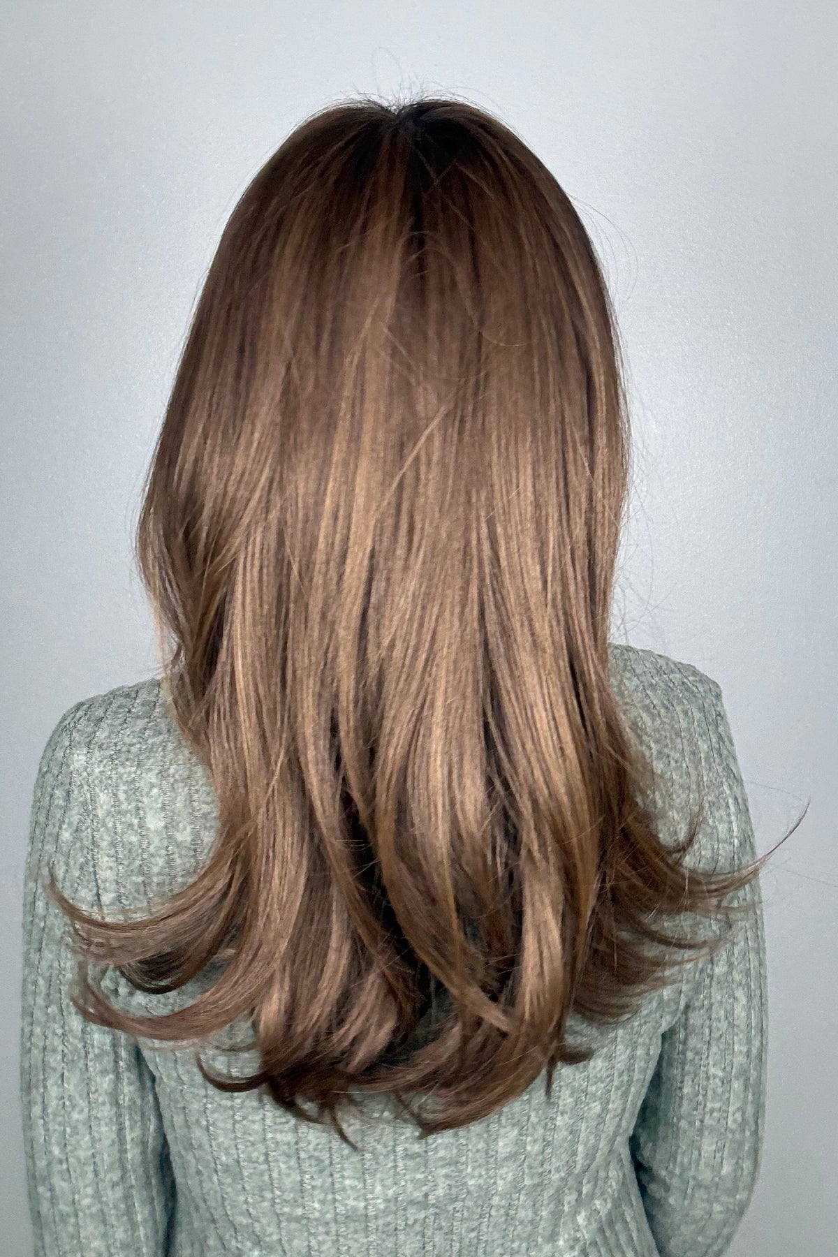 A woman with shoulder-length brown hair and bangs, wearing a textured light gray knit sweater (All Grown Up by Toni Brattin in color Light Brown).