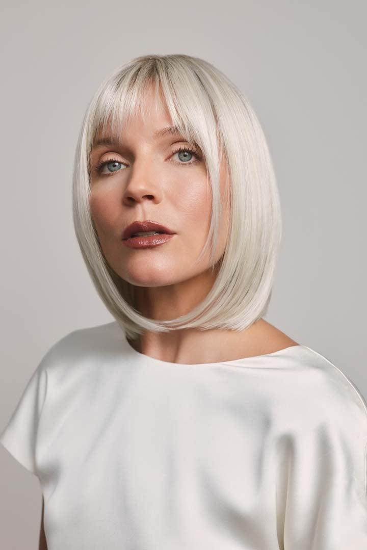 Ami by Noriko synthetic lace front bob wig in a sleek platinum blonde shade with face-framing layers and bangs.
