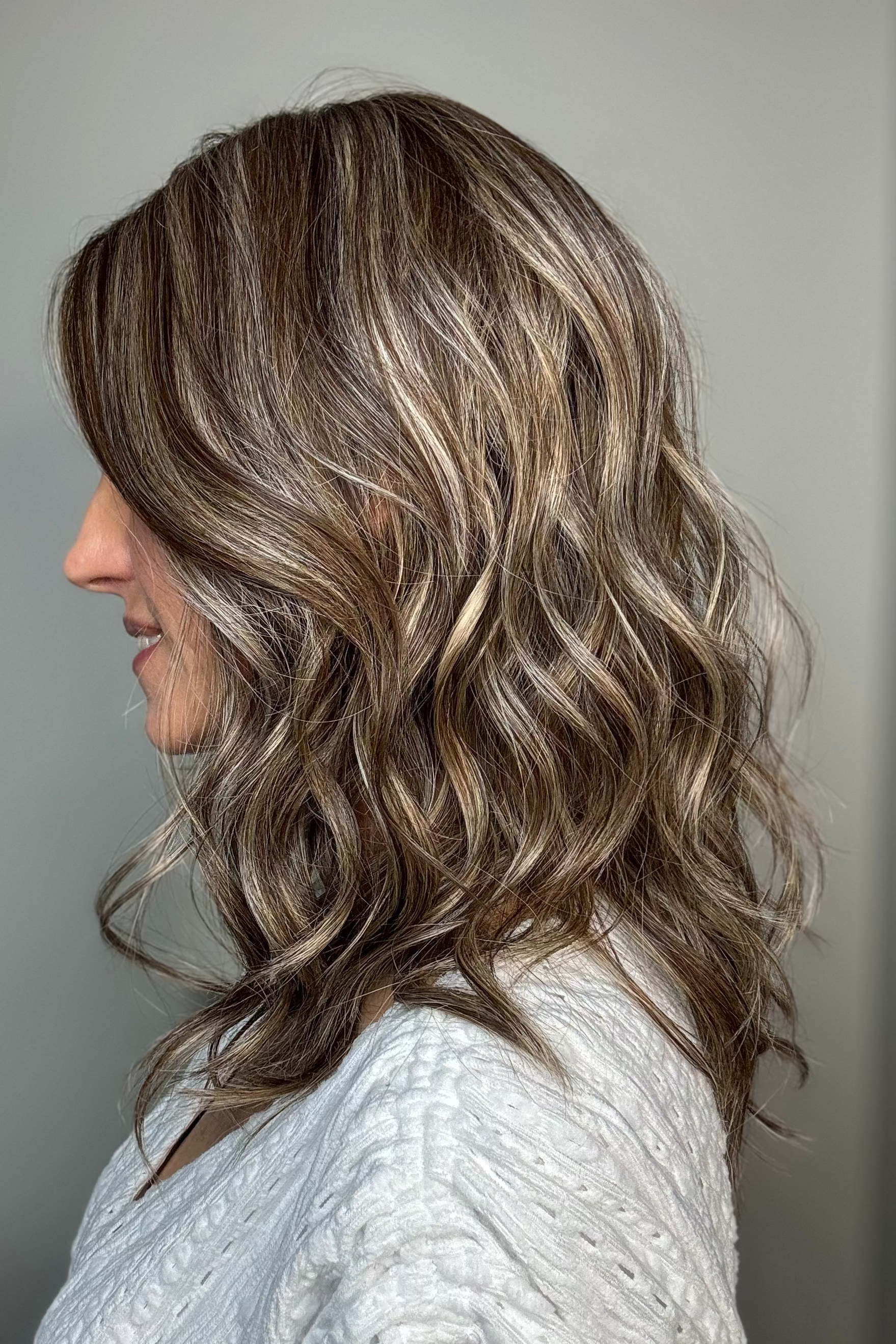 Woman wearing wavy shoulder-length wig (Maude by Amore in Tres Chocolate R)