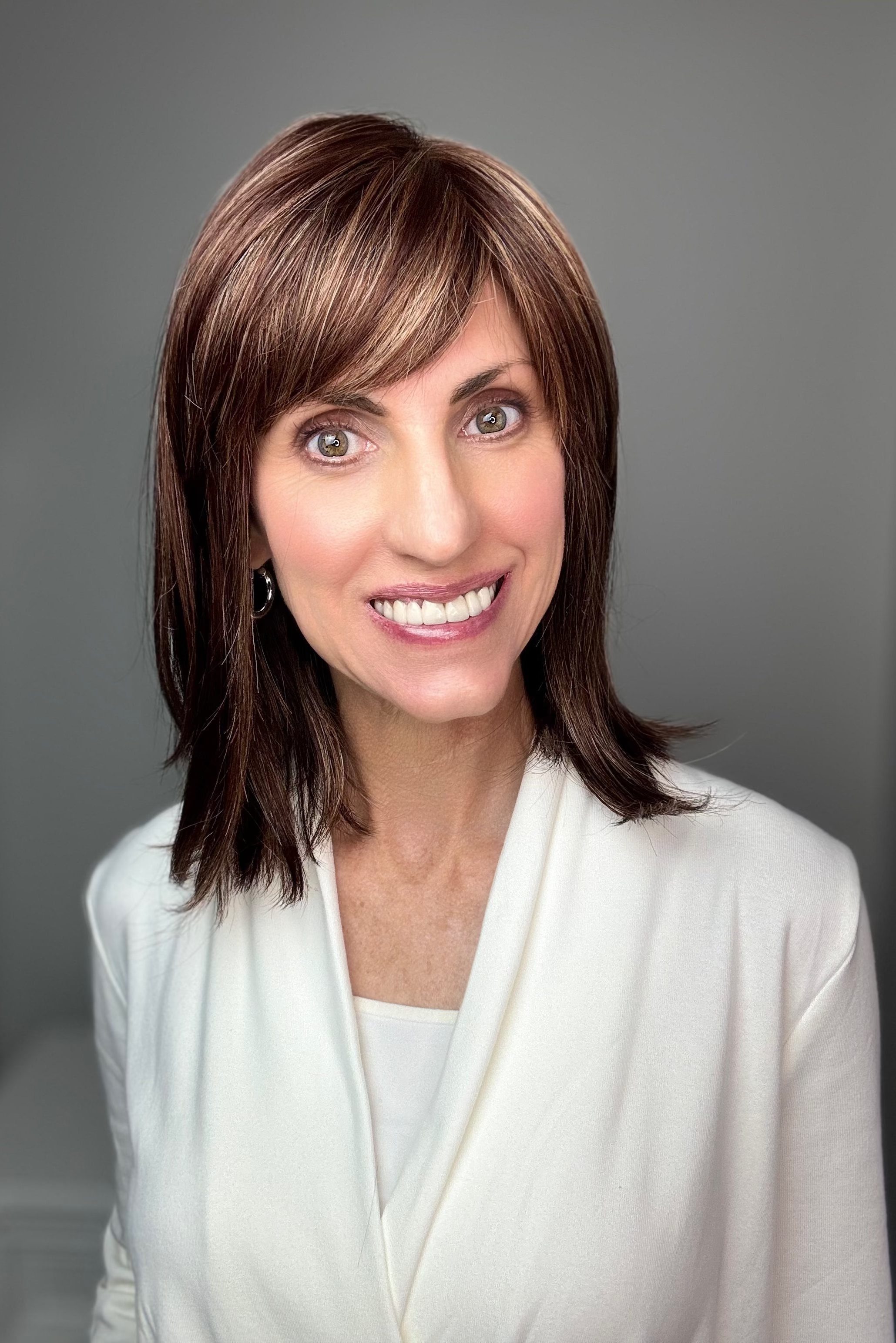Woman with shoulder-length brown wig with bangs (Tatum by Amore in Auburn Sugar)