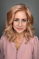 A woman with shoulder-length wavy pink wig (Avalon by Estetica in color Smoky Rose).