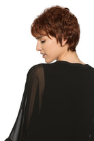 Woman wearing Aubrie synthetic pixie wig by WigPro in color 32/130 wearing a black top against a white background - left side/back view