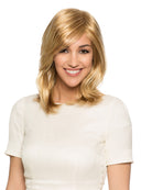Woman wearing Diane synthetic wig by WigPro in a golden blonde color with a white shirt and white background - Front view