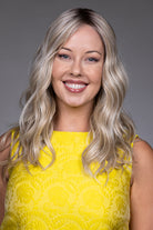 Bella by Belle Tress long blonde wavy synthetic wig with lace front and monofilament top on a smiling woman.